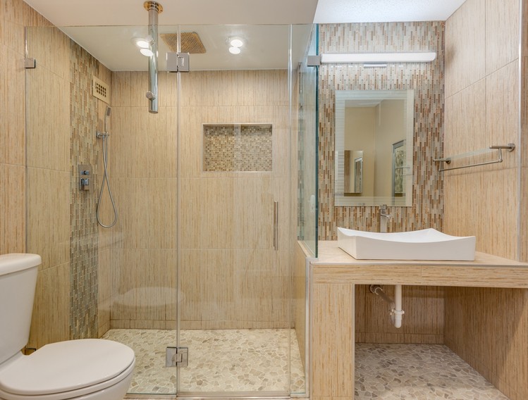 Bathroom after remodel - frameless glass walk-in shower with a rain showerhead, pebble floor and vessel sink vanity