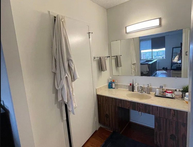 Bathroom before remodel - dated vanity with a cultured-marble top and a wall mirror