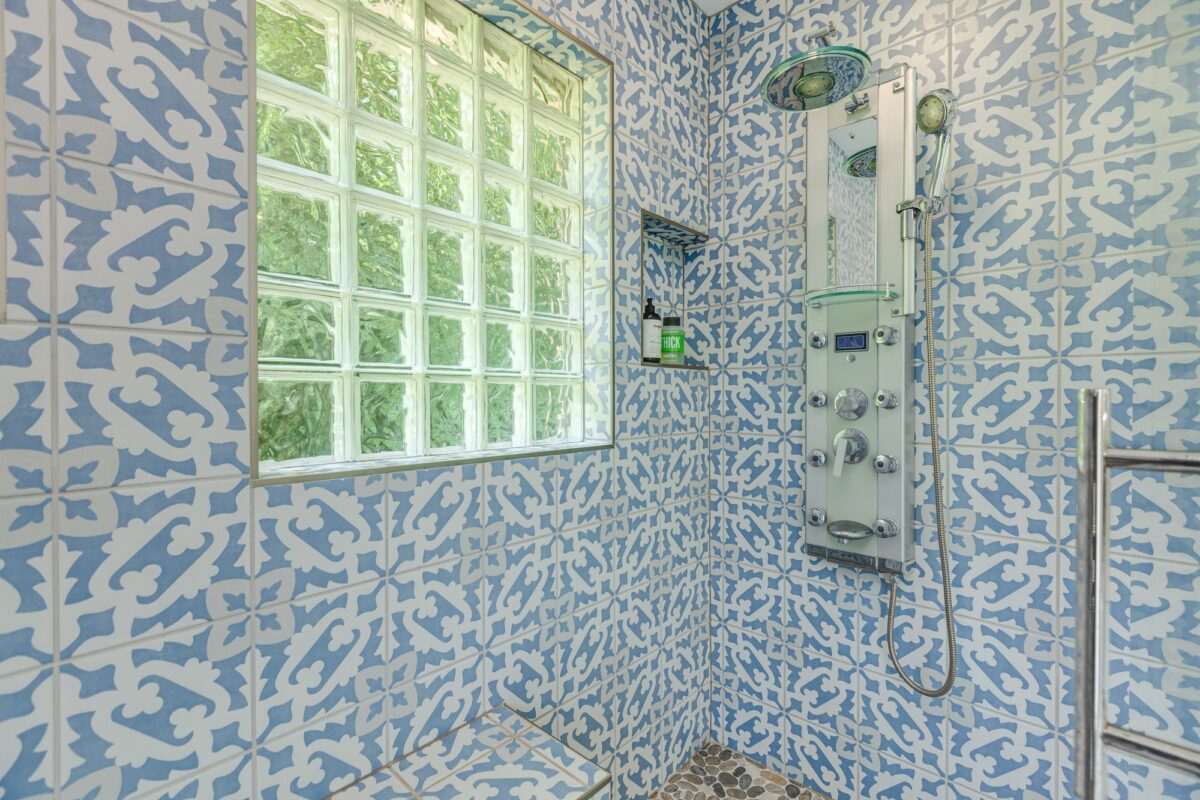 Blue and white patterned tile shower with glass block window and shower panel