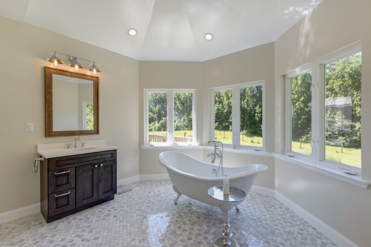 Bathroom with clawfoot tub, pebble tile floor and windows on three sides